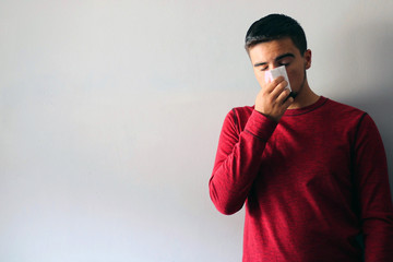 Health and Medicine Concept: Man dressed in red blowing his nose. Cold boy.