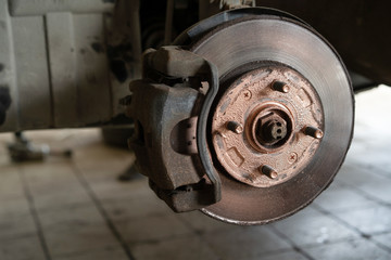 Old worn brake discs on a passenger car. Car on a lift in a car service.
