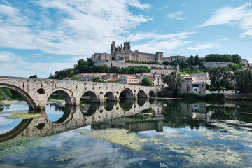 The old Roman Bridge and the city of Beziers in France reflected in the waters of the River Orb