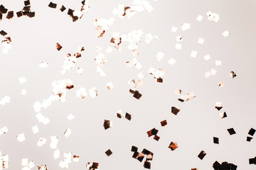 Falling silver confetti on grey backdrop. Holiday concept.