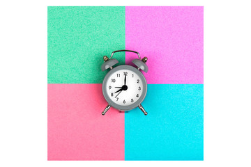 Clock with an alarm clock on a white background lie on colored paper sheets of green, blue, lilac and pink for notes