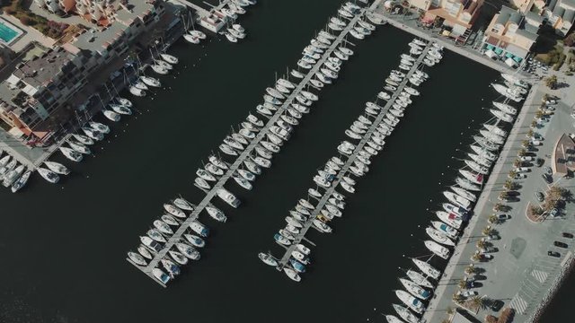 Aerial drone flying out over a marina for boats and tourist ships. Many yachts in French docks.