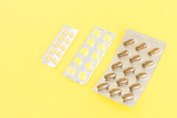 Medicine pills, capsules on yellow background.Concept of medicine.Medicines for the treatment of diseases, viruses, autumn cold season, beriberi, hypothermia, vaccination