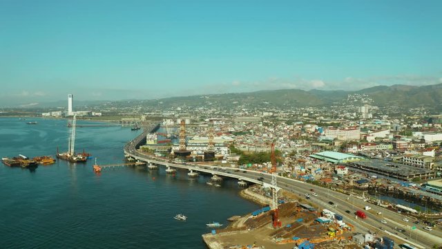 City of Cebu top view, the port in the harbor and cargo ships and a highway with cars near the sea. Philippines, Cebu.