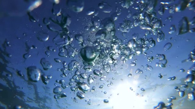 Underwater slow motion video of diver releasing air bubbles flowing towards sea surface in tropical exotic bay