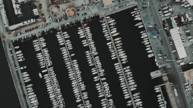 Aerial drone flying out over a marina for boats and tourist ships. Many yachts in French docks.