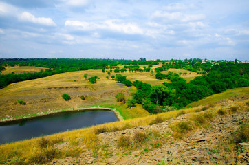 Fototapeta na wymiar Natural countryside landscape overlooking a small pond and rolling hills.