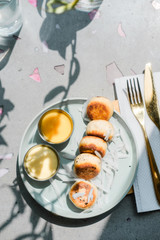 Vegan tofu cheese pancakes on blue plate, gray concrete table. Direct sun light, focus on shadows. Food blog photography concept. Overhead