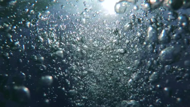 Underwater slow motion video of diver releasing air bubbles flowing towards sea surface in tropical exotic bay