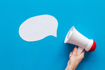 loudspeaker in hand with bubble for announcement text on blue background top view mock up