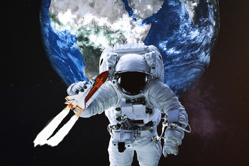 Fototapeta na wymiar Astronaut with flying shuttle in his hand in a front of Earth planet of solar system. Science fiction. Elements of the image were furnished by NASA