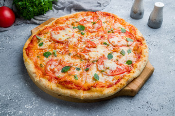 Italian pizza Margherita with tomatoes and basil on beautiful grey table