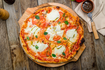 Italian pizza Margherita buffalo with tomatoes, mozzarella and basil on old wooden table top view