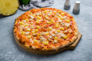 pizza Hawaiian with pineapple and chicken on beautiful grey table