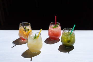 Side view of various of refreshing summer lemonades: classic lemon soda, strawberry lemonade,...