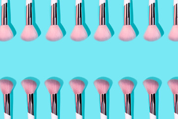 Pattern made of make up white brush on turquoise background. Minimal beauty concept.