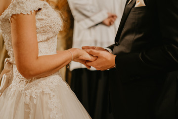 Bride and groom holding hands before the priest
