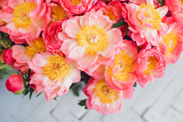 Coral peonies in a glass vase on a table. Beautiful peony flower for floral shop concept. Fresh cut bouquet. Flowers delivery. Copy space