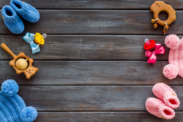 Cute baby clothes for girl and boy, rattle and dummy on wooden background top view copyspace