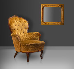 Empty worn vintage upholstered armchair in sparse environment with golden picture frame on wall