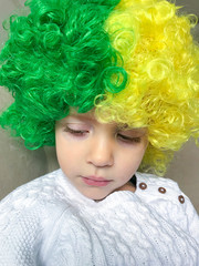 Child with green and yellow wig celebrating brazil game and independence.