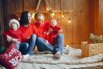 Cute family have fun in decorating room. Beautiful mother with little children and husband. Family in a red sweaters