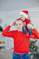 Cute family have fun in decorating room. Handsome father with little son. Family in a red sweaters