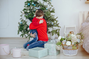 Naklejka premium Cute family have fun in decorating room. Beautiful mother with little son. Family in a red sweaters