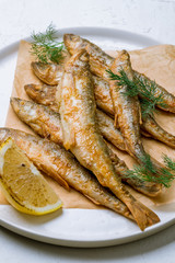 fried surmullet on white plate on white concrete table