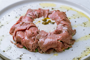 vitello tonato on a plate on white concrete table