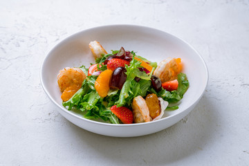 salad with vegetables and tiger prawns on white concrete table