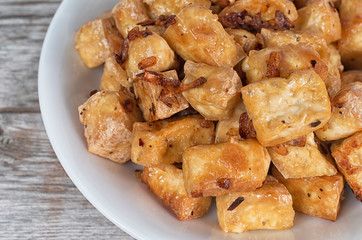 Chinese deep fried tofu cubes on a wooden table, a favorite meal for vegetarians