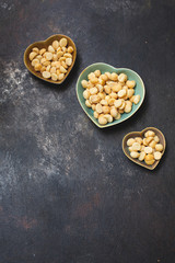 Macadamia Nuts in Heart-Shaped Bowls on Black Textured Background