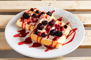 Waffle with cream, fruits and syrup.