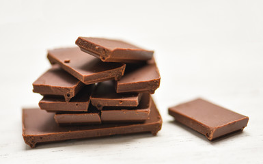 chocolate bar stacked on the white wood background - close up Chocolate pieces candy sweet dessert and snack , selective focus