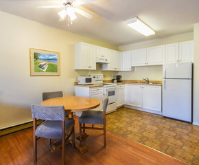 Modest white kitchen with the table and chairs in dinner area.