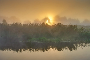 Obraz na płótnie Canvas Orange sunrise over river surface with fog. River landscape in summer morning