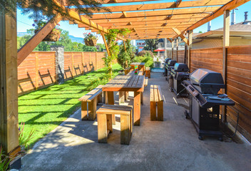Barbecue and picnic area of hotel with row of tables and grills under the shed.