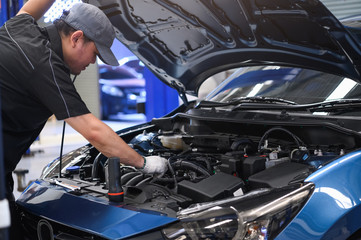 Fototapeta na wymiar Asian male auto mechanic examine car engine breakdown problem in front of automotive vehicle car hood. Safety technical inspection care check service maintenance for customer before long road trip