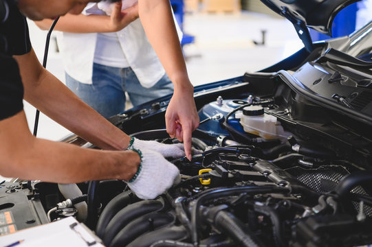 Asian male auto mechanic examine car engine breakdown problem in front of automotive vehicle car hood with female customer. Safety technical inspection care check service maintenance for road trip