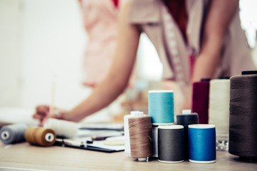 Closeup of colorful thread with fashion designer background in workshop studio. Stylish fashionista woman creating new cloth design collection. Tailoring and sewing People lifestyle and occupation