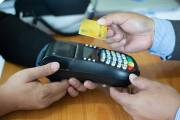 Close up of hands businessman use a credit card swipe to pay for the share transfer fees in the investment of the company.concept of payment