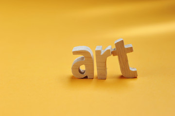 Word ART carved from wood stand on yellow backdrop for your desing, Art text
