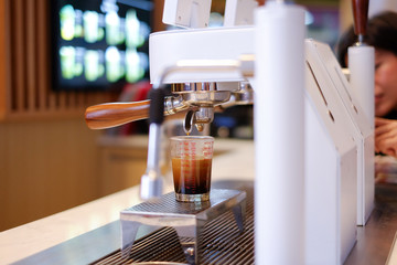 A glass of iced coffee upper layer is espresso lower is fresh milk blur background with selective focus.