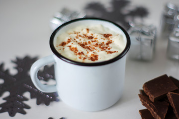 Cup of hot chocolate on a white wooden table. Traditional christmas drink, snowflakes and presents.