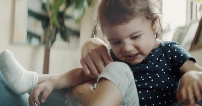 Mother playing with daughter at home on the couch. Real life, candid footage. Shot in 4K RAW on a cinema camera.