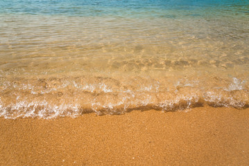 Fototapeta na wymiar Small wave on the beach close up in daytime