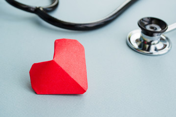 Cardiology and medical concept. Red heart and stethoscope on a light blue background.	