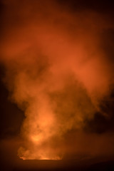 Smoke and gasses glow bright orange and yellow as the come out of a pit of lava at Volcanoes National Park  on the big island of Hawaii