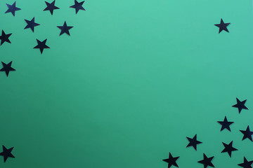 Star shaped confetti on a green background. Festive background. Holiday concept. Top view, flat lay.